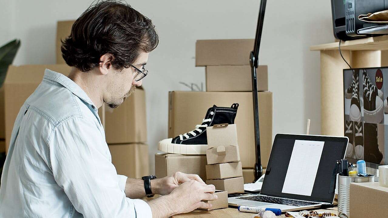 Ein Mann sitzt an seinem Arbeitsplatz und testet Hardware, umgeben von Kartons